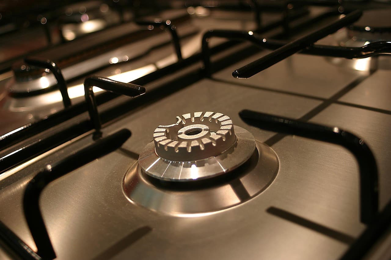 A lit gas burner on a stainless steel hob